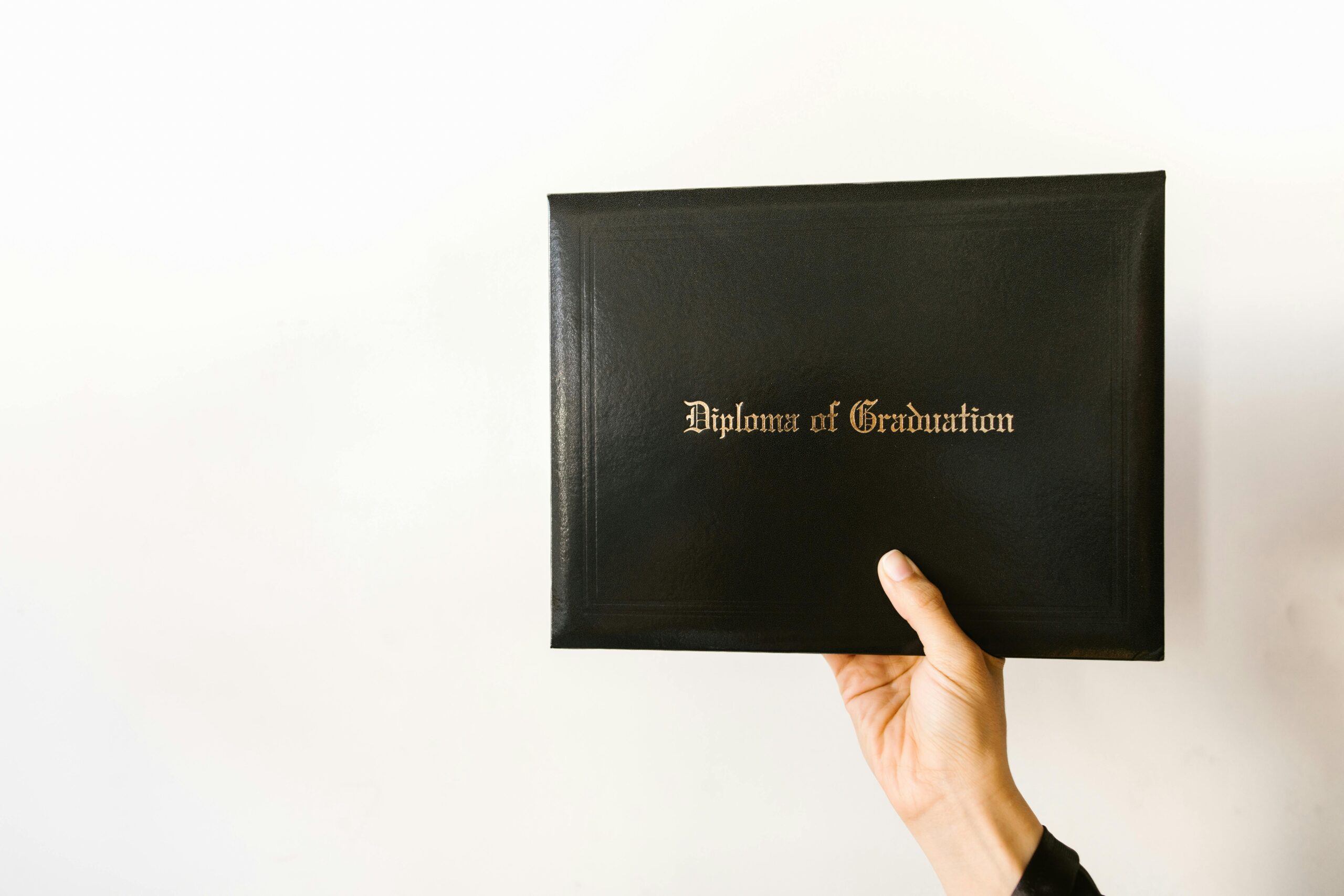 Close-up of a hand holding a graduation diploma with elegant typography.